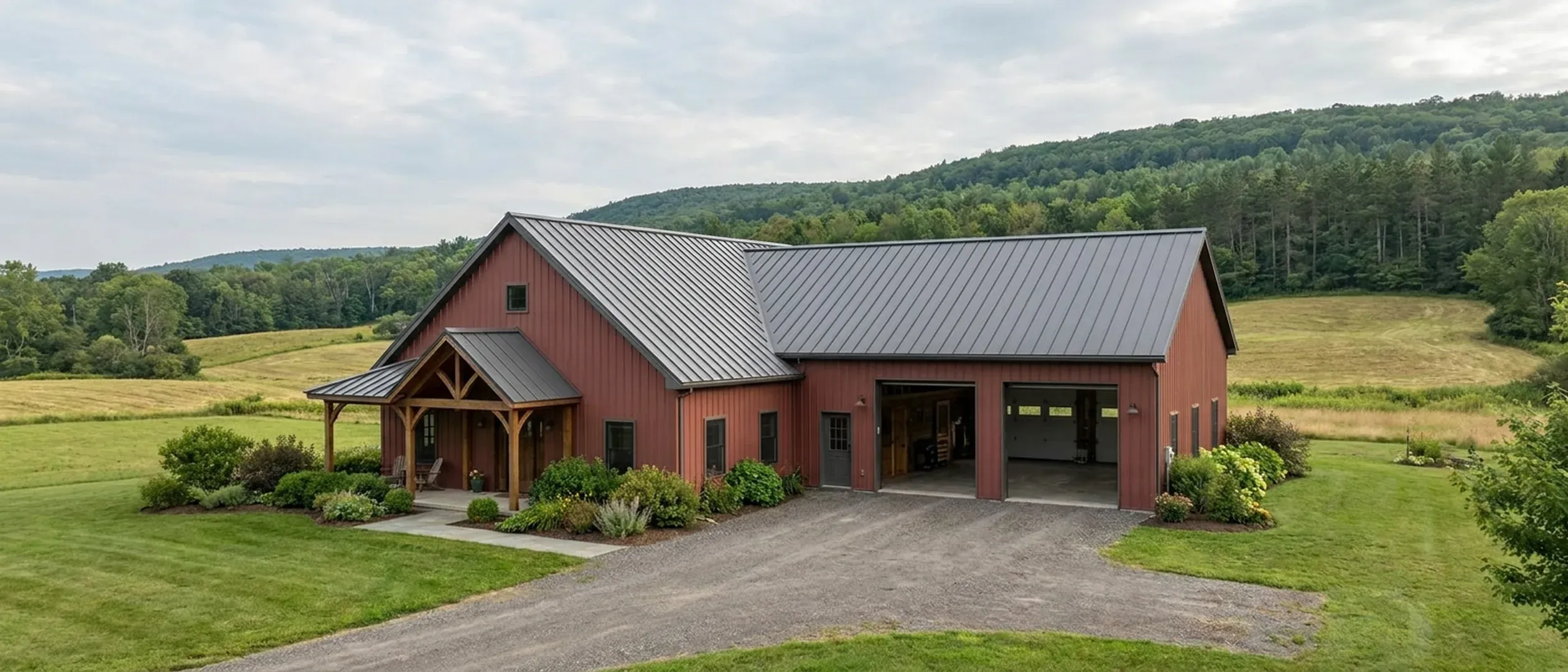 A completed barndominium with a covered entry porch and an attached shop bay, photographed in flat overcast daylight.